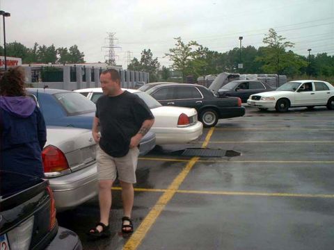 2000 Ford Crown Victoria - Several Ford Crown Victorias are parked in a wet lot, with a man standing beside one of them.