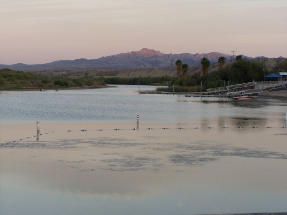 Calm river or lake at dusk with mountains and a boat dock