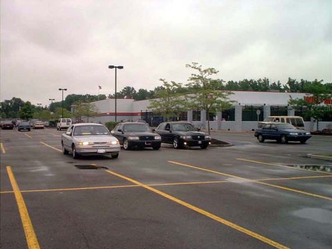 2000 Ford Crown Victoria - Several cars are parked in a lot on a cloudy day, with a store in the background.