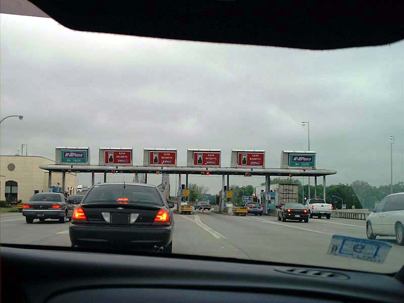 Black 2000 Ford Crown Victoria at a toll plaza, rear view. Brake lights are on
