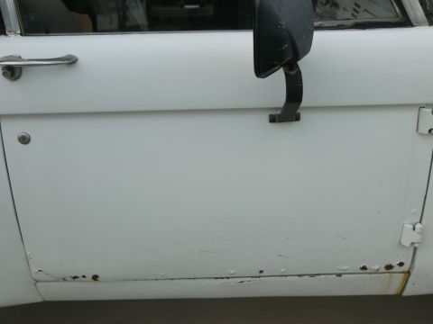 1974 Ford Bronco - Close-up of a 1974 Ford Bronco's side door, showing the handle, mirror, and signs of rust.