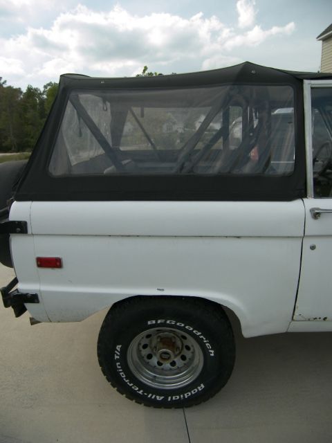 1974 Ford Bronco - This 1974 Ford Bronco is seen from the side, showing its white body and black soft top with a spare tire on the rear.