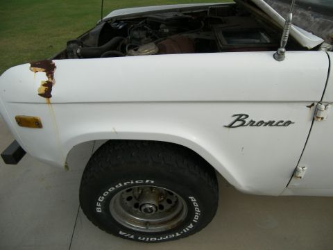 1974 Ford Bronco - A white 1974 Ford Bronco is shown with its hood open, revealing the engine compartment.