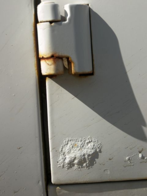 1974 Ford Bronco - White door hinge showing extensive rust and paint damage.