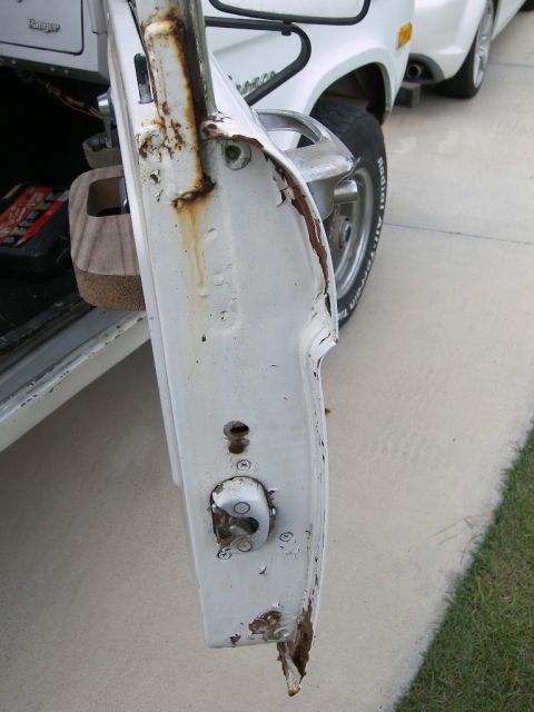 1974 Ford Bronco - The door jamb of a white 1974 Ford Bronco shows significant rust and damage.