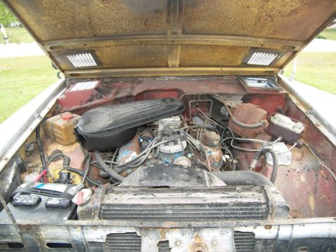 1974 Ford Bronco - The engine bay of a 1974 Ford Bronco is visible with the hood open, revealing the V8 engine and associated components.