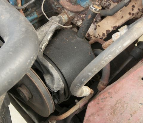 1974 Ford Bronco - Close-up view of engine components, including a mount and hoses, showing signs of age and use.
