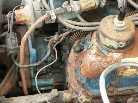 1974 Ford Bronco - Close-up view of a heavily rusted engine bay with blue painted components visible.