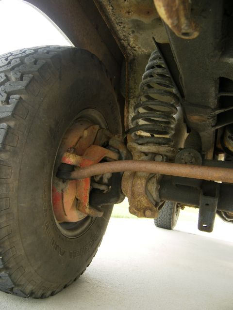 1974 Ford Bronco - Close-up of the front suspension and tire assembly of an older vehicle.