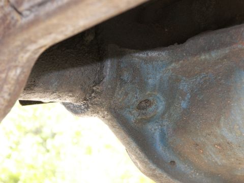 1974 Ford Bronco - Close-up view of a vehicle's undercarriage, showing rusted and painted metal parts.