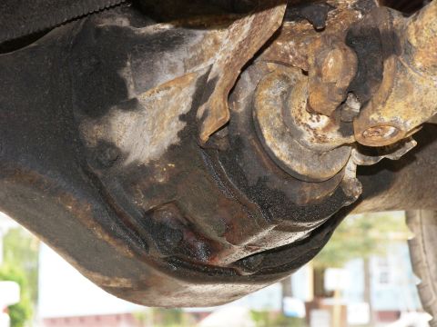 1974 Ford Bronco - Underside view of a vehicle's differential housing and U-joint, showing wear and rust.