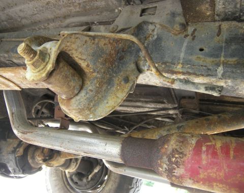1974 Ford Bronco - Undercarriage view of a heavily rusted vehicle, focusing on suspension and exhaust system components.