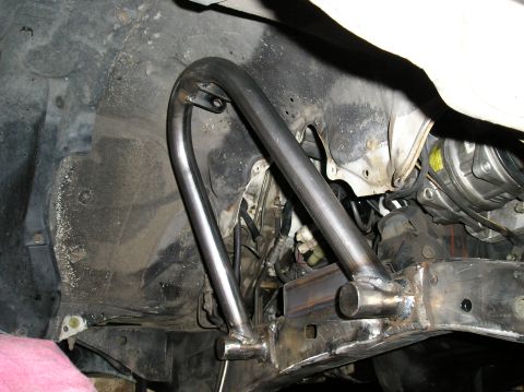 1986 Toyota Hilux - Custom front shock hoops are welded onto the vehicle's frame, with suspension and engine parts visible in the background.