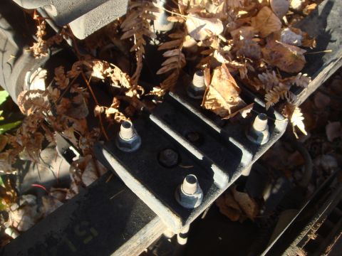 1996 Ford Bronco - A close-up view of a metal bracket and bolts, partially obscured by fallen leaves.