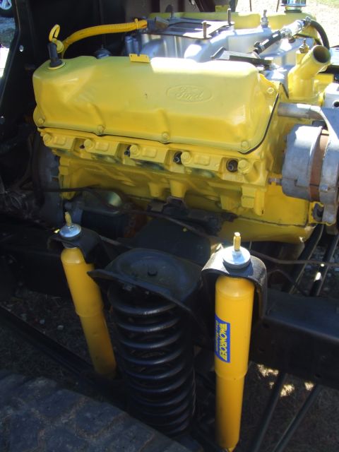 1979 Ford Bronco - Close-up of a Ford V8 engine, painted yellow, with visible Monroe shocks and suspension components.