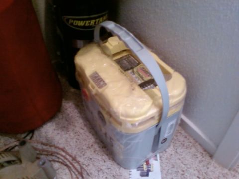 1995 Ford Bronco - Car battery wrapped in plastic, with a black tank visible in the background.