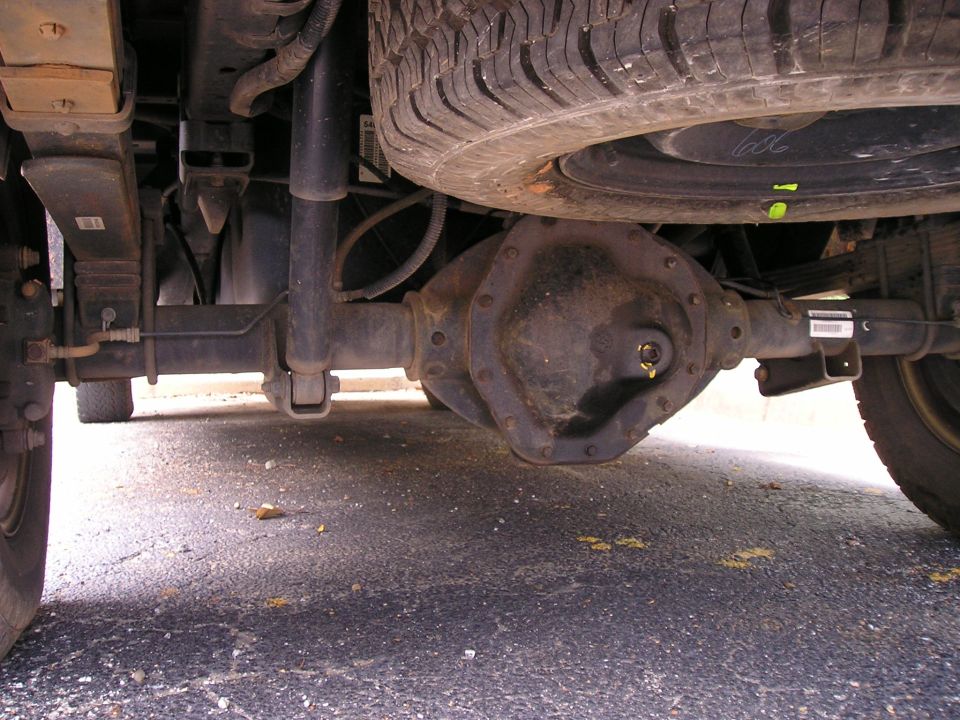Underside view of a truck rear axle, differential cover, leaf spring and shock