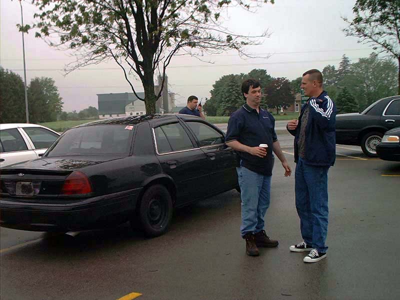 2000 Ford Crown Victoria parked on wet asphalt, two men standing nearby