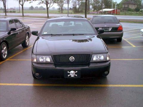 2000 Ford Crown Victoria - A black Mercury Grand Marquis is parked in a lot, displaying a skull and crossbones license plate.