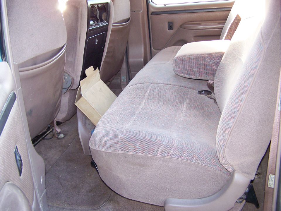 Interior shot of a truck's back seat area, showing brown fabric seats and a center console