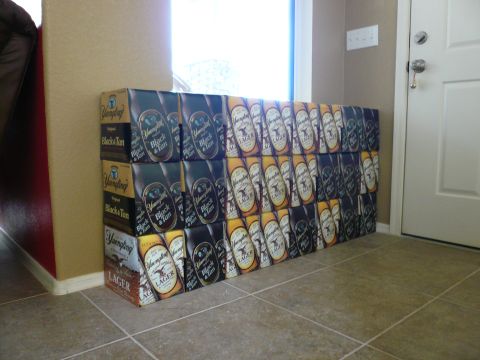 1996 Ford Probe - A large collection of Yuengling beer cases, including Black & Tan and Lager varieties, are neatly stacked against a wall near a doorway.