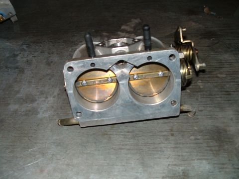 1995 Ford Bronco - A close-up view of a dual throttle body assembly, showing the internal butterfly valves and linkage mechanism.