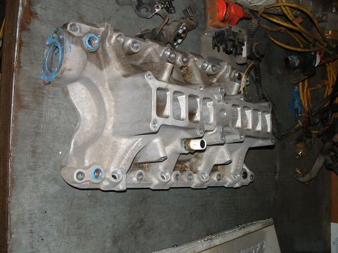 1995 Ford Bronco - Close-up of an aluminum intake manifold, likely from a Ford vehicle, with visible blue gasket material around the ports.