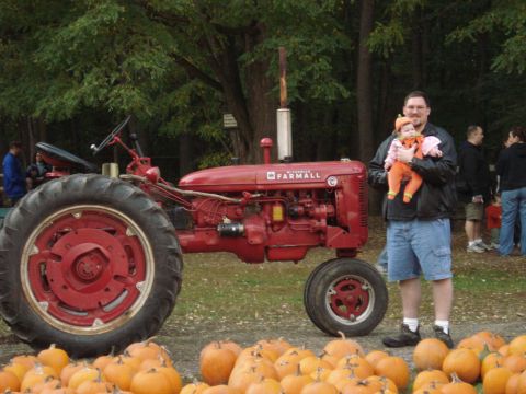 2000 Ford Crown Victoria - A man holds a baby while standing next to a vintage McCormick Farmall tractor at a pumpkin patch.