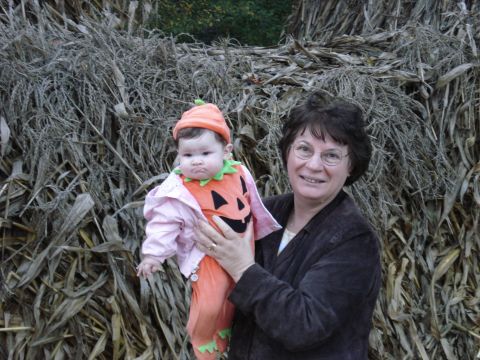 2000 Ford Crown Victoria - A woman holds a baby dressed in a pumpkin costume in front of a backdrop of dried corn stalks.