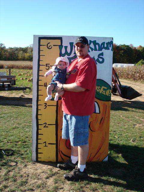 2000 Ford Crown Victoria - A man and a baby pose in front of a large ruler at a pumpkin patch.