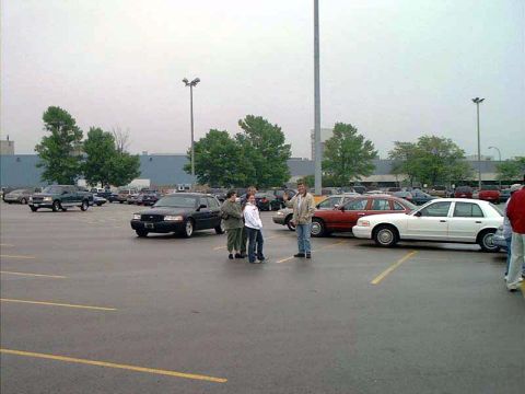 2000 Ford Crown Victoria - Several vehicles are parked in an outdoor lot under an overcast sky.