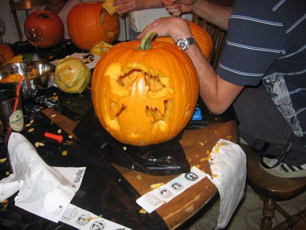 Carved pumpkin with a face on a table with pumpkin guts and carving tools