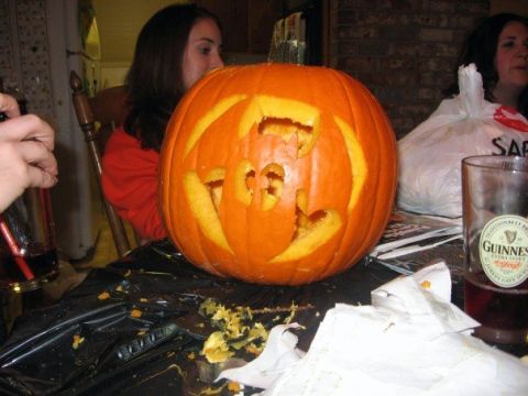 1989 Ford Bronco - A carved pumpkin sits on a table, surrounded by party remnants and people enjoying an evening.