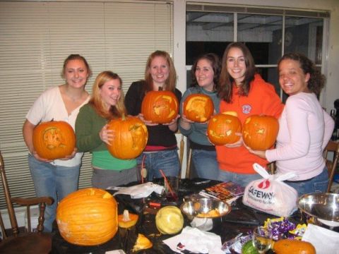 1989 Ford Bronco - Six women pose for a photo while holding carved pumpkins, with a table full of Halloween carving supplies in front of them.