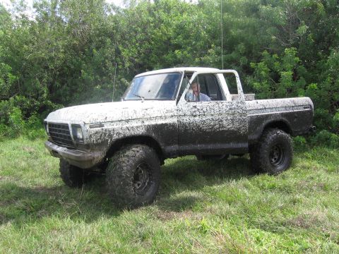 1979 Ford F-150 - A driver is visible inside the heavily mud-covered 1979 Ford F-150 pickup truck.