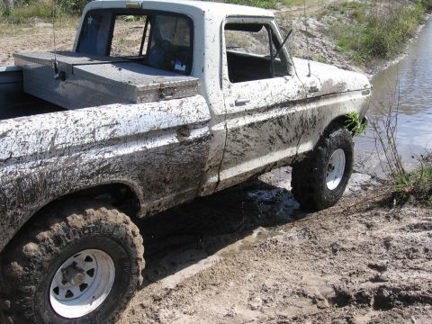 1979 Ford F-150 - Mud-covered 1977 Ford F-150 navigates a wet, muddy terrain, with its tires deep in the mire.