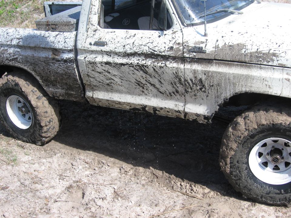 Mud-splattered 1979 Ford F-150 pickup truck driving through mud