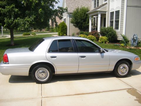 2001 Ford Crown Victoria - A silver 2001 Ford Crown Victoria sedan is parked in a suburban driveway.