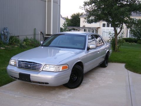 2001 Ford Crown Victoria - A silver 2001 Ford Crown Victoria sedan is parked in front of a house.