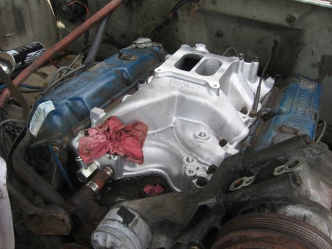 1979 Ford F-150 - Overhead view of a Ford V8 in the engine bay with a bare aluminum Edelbrock dual-plane intake manifold freshly bolted between blue Ford Pow…