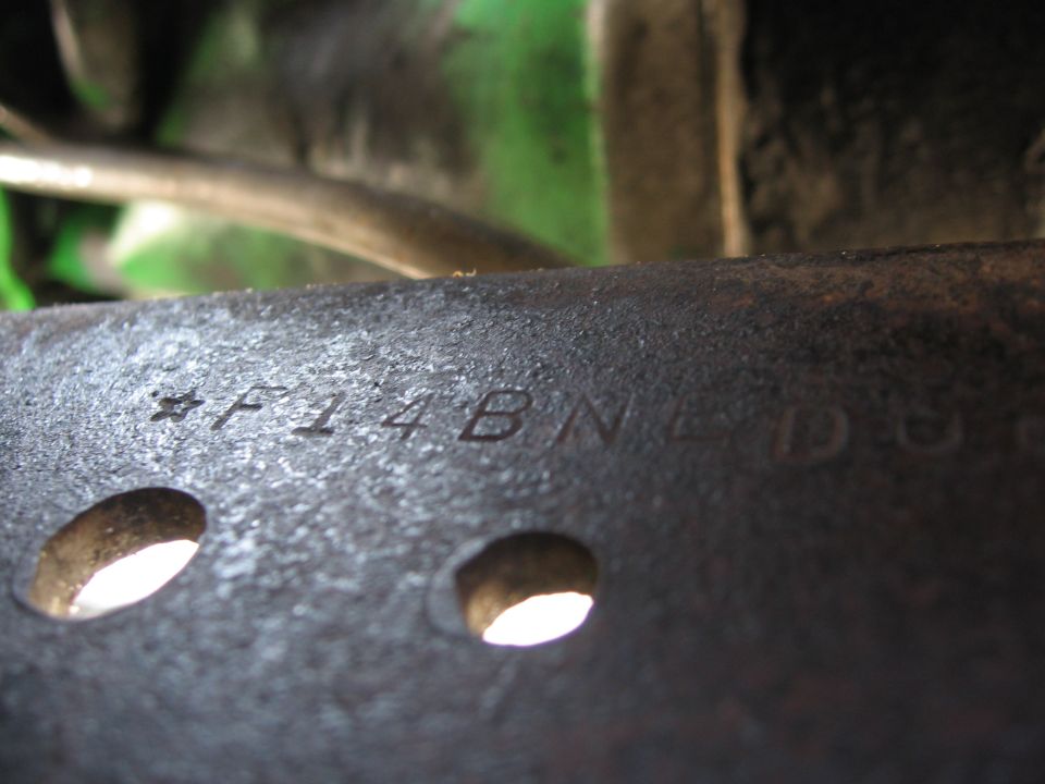 Close-up of a metal part with stamped text including *F14B and part of NDU