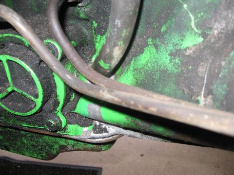 1979 Ford F-150 - Close-up view of an engine component, showing green and black paint with metal tubing and accumulated grime.