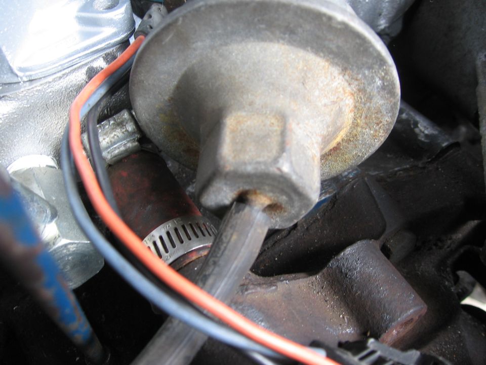 Close-up of a fuel pump with red and gray wires connected, near a hose clamp