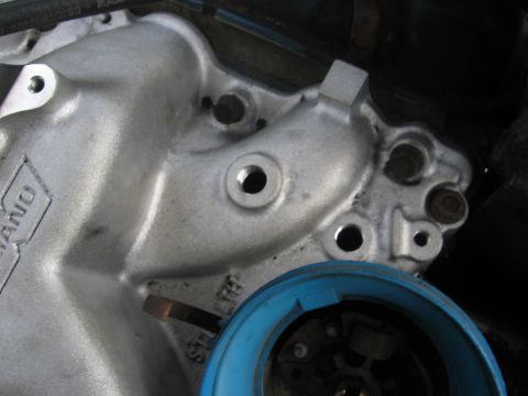 1979 Ford F-150 - Tight close-up of the front of a bare cast aluminum intake manifold showing raised cast lettering, open bolt bosses and threaded holes, wit…