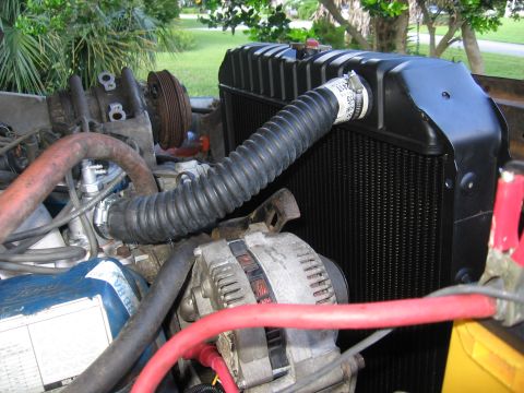 1979 Ford F-150 - Close-up of a black radiator newly installed in a truck with a flexible accordion-style upper hose clamped to the filler-neck side, alongsi…