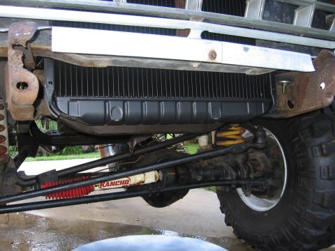 1979 Ford F-150 - Low-angle view under the front of a lifted 4x4 truck showing the radiator and lower air deflector behind the chrome bumper, with the solid…