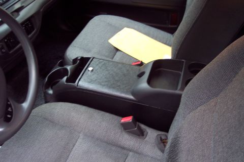 2001 Ford Crown Victoria - The interior of a car features fabric seats and a center console with multiple cup holders and storage compartments.