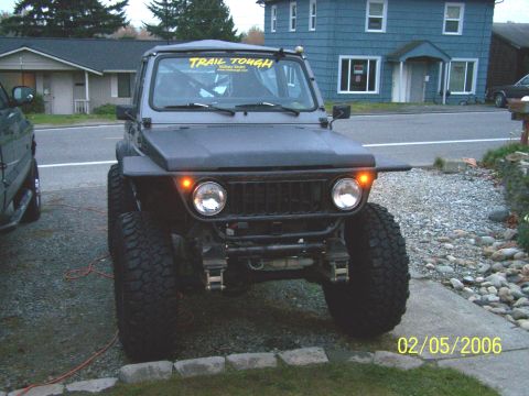 1988 Suzuki Samurai - This heavily modified off-road SUV features oversized tires and a "TRAIL TOUGH" banner, suggesting it's built for terrain.