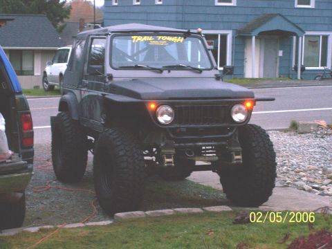 1988 Suzuki Samurai - This heavily modified 1988 Suzuki Samurai is parked in front of a building with another vehicle visible.