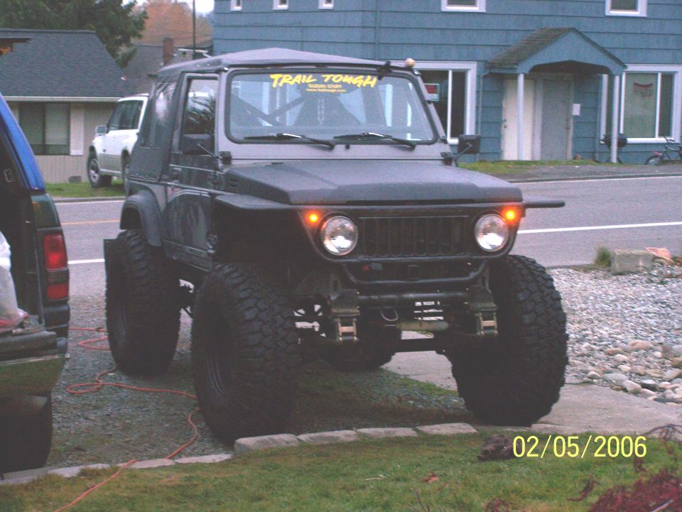 Lifted 1988 Suzuki Samurai with big tires and a 'Trail Tough' sticker on the windshield